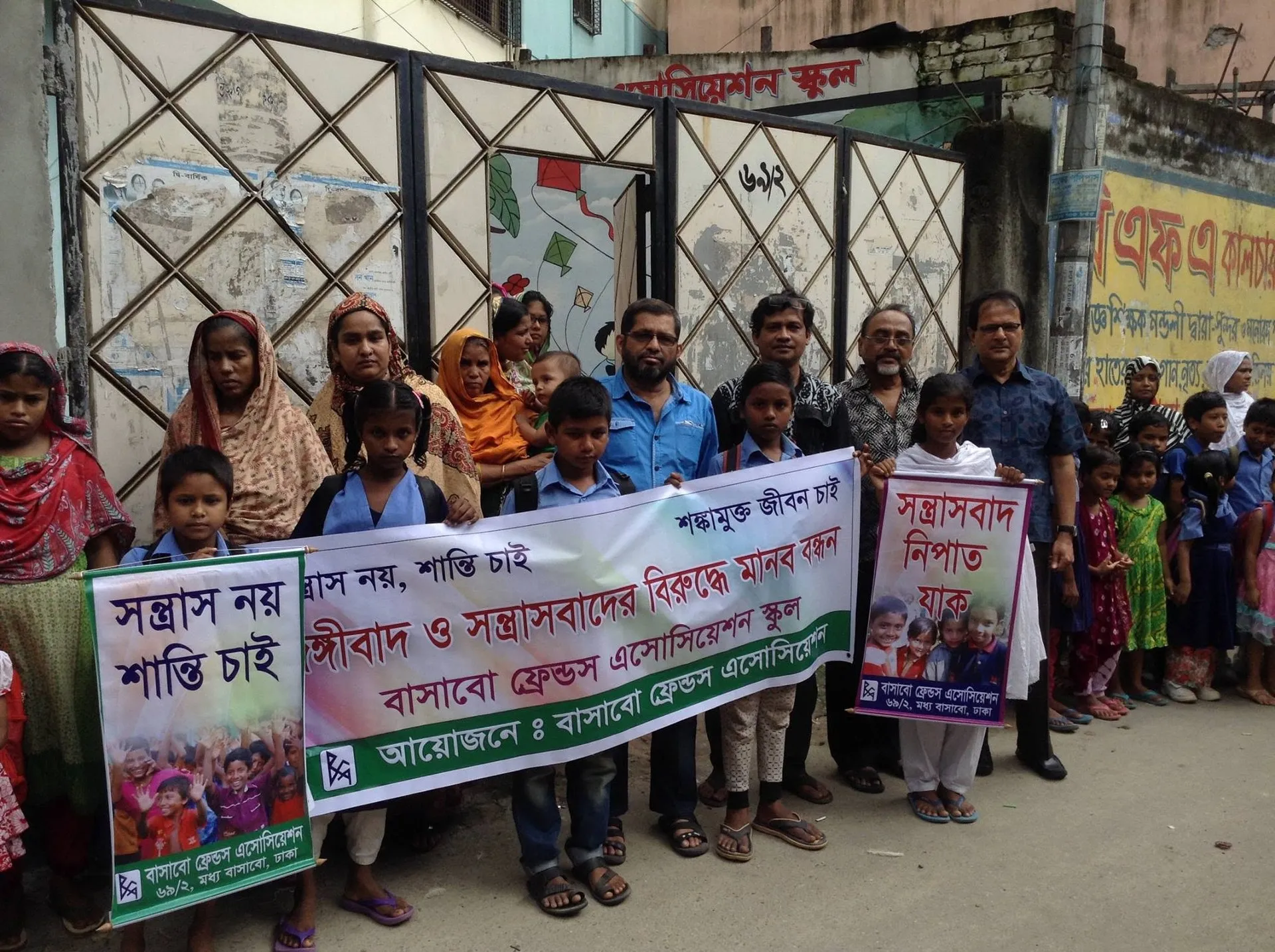 Children and adults holding a human chain banner in front of the BFA school gate