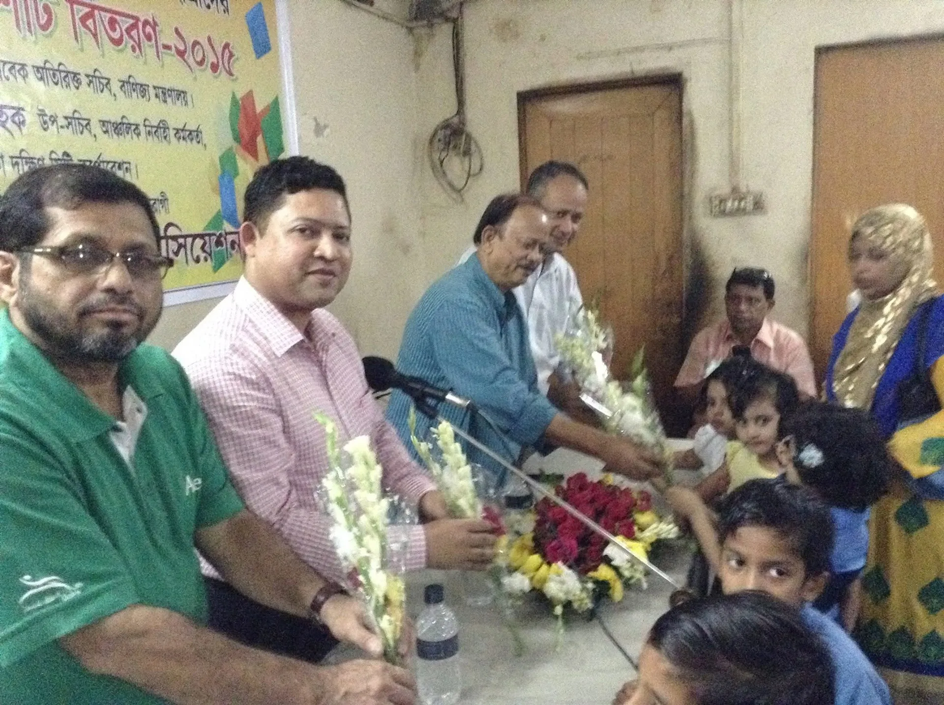 Guests at a table present gifts to young children at the uniform distribution ceremony